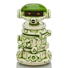 a green and white robot toy sitting on top of a reflective surface with its head turned to the side