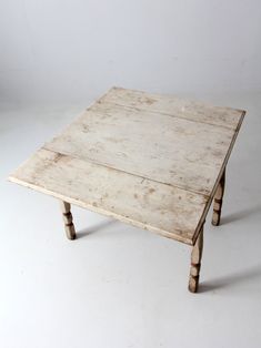 an old wooden table sitting on top of a white floor with no one around it