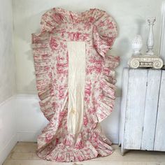 a large pink dress sitting on top of a wooden floor next to a white cabinet