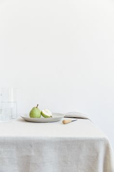 two pears are sitting on a plate next to a glass of water and a knife