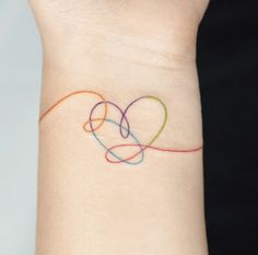 a woman's wrist with a colorful heart tattoo on her left arm and the word love written across it