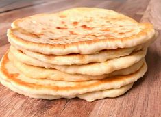 a stack of flat bread sitting on top of a wooden table