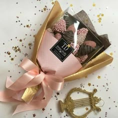 a pink and gold gift box filled with chocolates