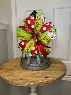 a red and green christmas bow on top of a wooden table in front of a door