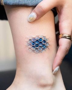 a woman's leg with a tattoo design on the back of her thigh, which is covered in blue water droplets