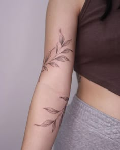 a woman's arm with a branch tattoo on the left side of her arm