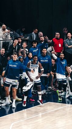 a group of men standing next to each other on top of a basketball court in front of a crowd