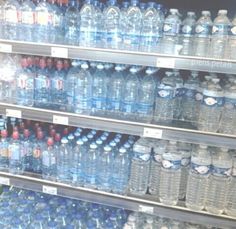 several rows of bottled water on shelves in a store