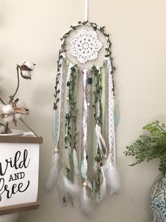 a white and green dream catcher hanging on the wall next to a potted plant