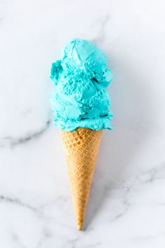 an ice cream cone with blue icing on a marble surface