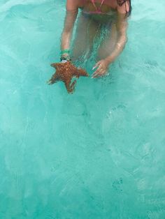 a woman is holding a starfish in the water