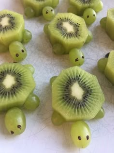 sliced kiwis and grapes on a white surface