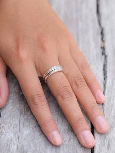 a woman's hand with a ring on it, sitting on a wooden surface