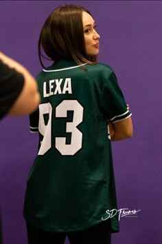 a woman wearing a jersey with the number 33 on it is standing in front of a purple wall