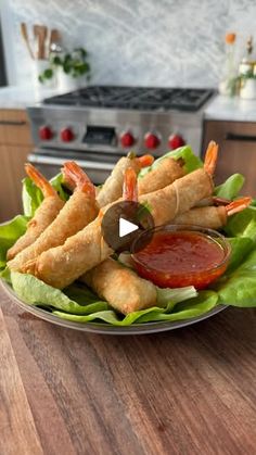 a plate full of food with dipping sauce on it and shrimp sticks in the middle