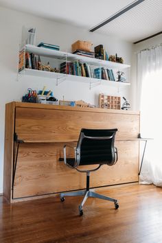 an office chair sitting in front of a desk with bookshelves and shelves above it