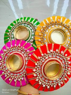 three different colored plates on a table with gold trimmings and jewelled decorations