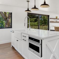 a kitchen with an island, sink and oven in it's center area next to a window