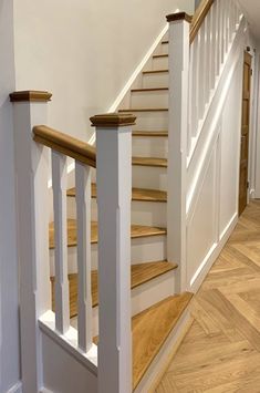 a white staircase with wooden handrails and wood flooring