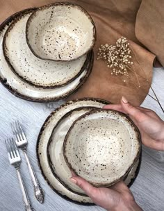 a person is holding three plates with silverware next to each other on a table