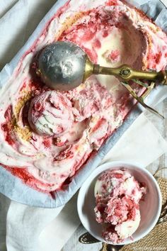 two scoops of ice cream sitting on top of a table next to a bowl