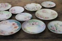 a table topped with lots of plates on top of a wooden table covered in flowers