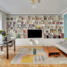 a living room filled with furniture and a flat screen tv mounted on a wall next to a wooden floor