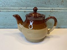 a brown and white tea pot with scissors on it