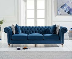 a blue couch sitting on top of a white floor next to a rug and window