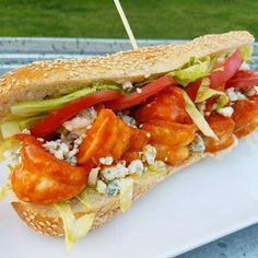 a sandwich with tomatoes, lettuce and other toppings on a white plate