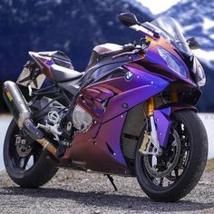 a purple motorcycle parked on the side of a road next to a body of water