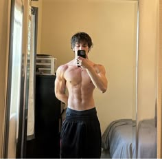 a shirtless man taking a selfie in front of a mirror with his cell phone