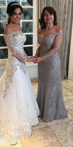 two women in dresses standing next to each other holding hands and posing for the camera