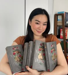 a woman holding five books in her hands