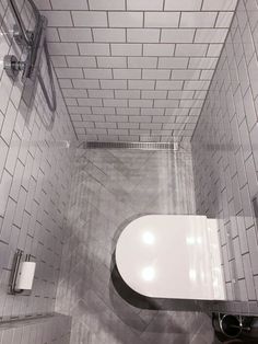 a white toilet sitting inside of a bathroom next to a walk in shower head mounted on a wall