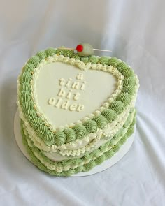 a green and white cake with a heart shaped frosting on the top that says, all we need is love