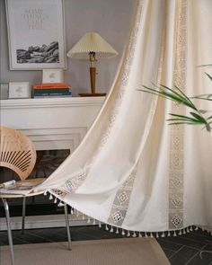 a room with a chair, lamp and window curtain in front of a fire place