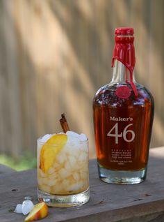 a bottle of maker's 46 sits next to a glass filled with ice and an orange slice