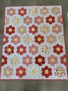 a red and yellow flowered quilt on the floor next to a pair of shoes