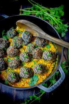 a skillet filled with meatballs covered in cheese and sauce next to parsley