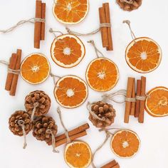 orange slices, cinnamon sticks and pine cones are arranged on a white surface with twine