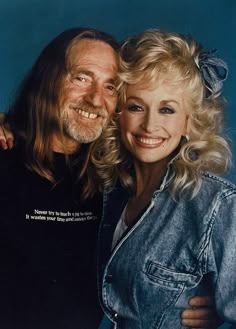 an older man and woman posing for a photo with their arms around each other, both smiling