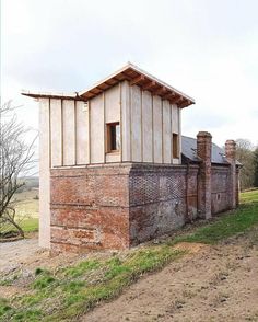 an old brick building sitting on the side of a dirt road next to a field