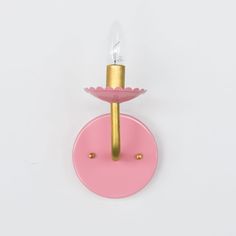 a pink and gold candle holder on a white wall