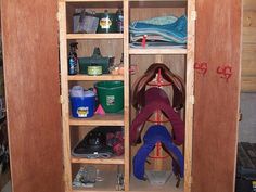 a wooden cabinet filled with lots of shoes and other items in it's storage area