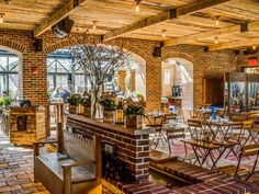 the inside of a restaurant with brick walls and exposed ceilinging, tables and chairs are arranged around an open fire place