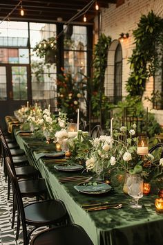 a long table is set up with candles and greenery for an outdoor dinner party