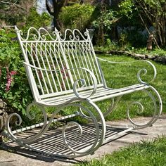 a white metal bench sitting in the grass