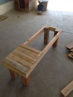 a wooden bench made out of pallets in a garage with other pieces of wood