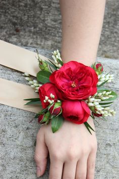 a woman's hand wearing a red flower wrist corsage